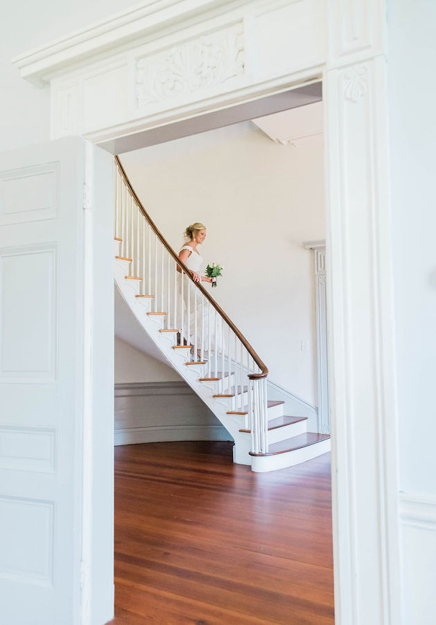 bride descending spiral staircase in historic home